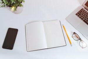 white open book on a white desk with laptop