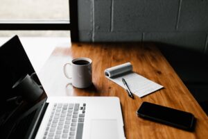 laptop, notepad, and coffee on wooden table